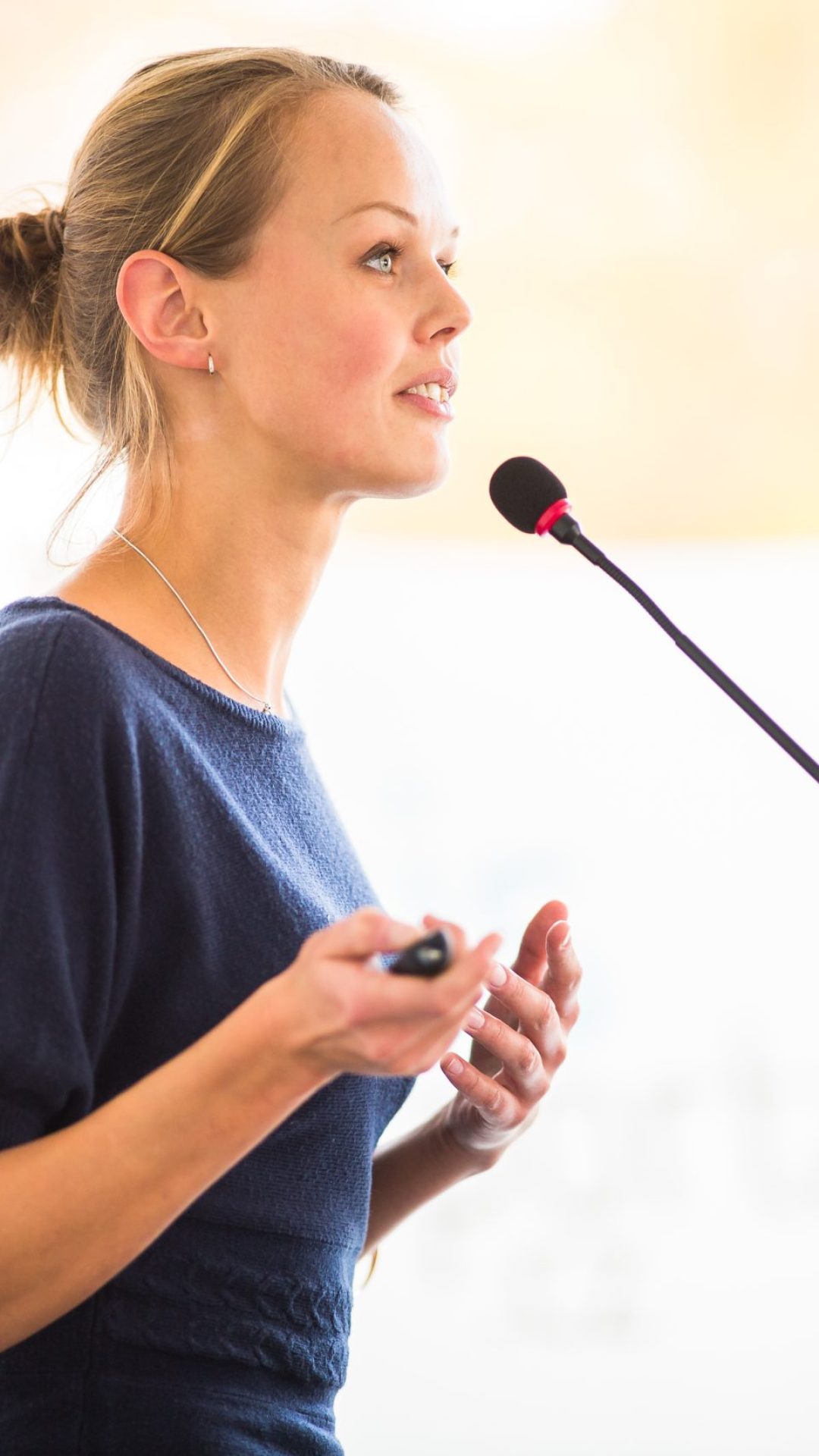 Pretty, young business woman giving a presentation in a conferen Pretty, young business woman giving a presentation in a conference/meeting setting (shallow DOF; color toned image)